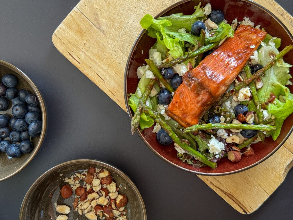 Miso Trout Salad with Blueberries & Greens: a fresh and colorful salad that brings together miso-glazed trout, crunchy roasted green asparagus, sweet blueberries, toasted hazelnuts, and creamy feta or ricotta — all layered over a bed of young greens and topped with a zesty vinaigrette. 