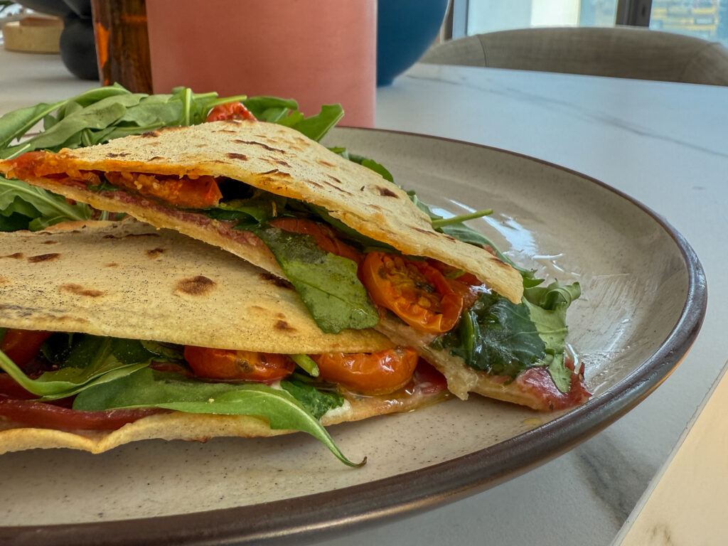 Some recipes remind us that the best things in life are often the simplest ones. The Piadina di Ravenna is one of those dishes — an Italian flatbread sandwich from Emilia-Romagna, filled with bresaola, mozzarella di bufala, and sun-dried tomatoes. Crisp on the outside, soft on the inside, and bursting with flavor, it’s the perfect recipe for a quick lunch, a light dinner, or a chic aperitivo shared with friends.